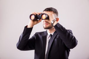 Businessman looking through binoculars isolated on white background